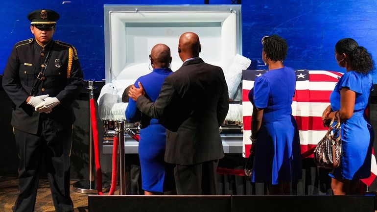 Mourners file past the casket of Dallas police officer Darron...