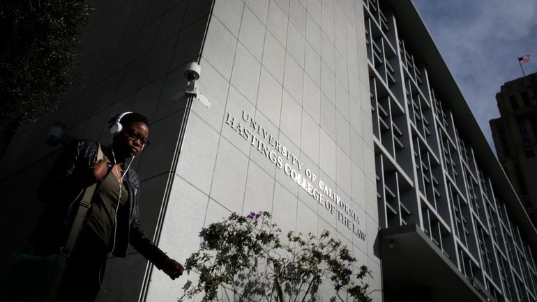 A pedestrian passes by the main building of the University...