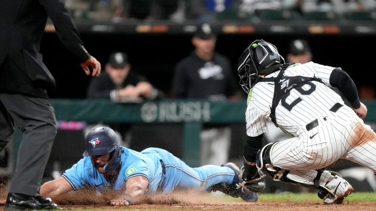 Toronto Blue Jays' Davis Schneider, left, scores next to Chicago...