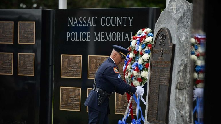 A police officer places a floral arrangement at the new...