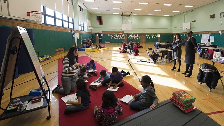 Reading teacher Stephanie Huggard works with her second-grade students in...