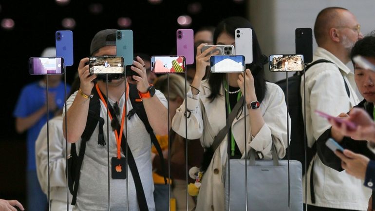 Attendees take a closer look at the Apple iPhone 16...