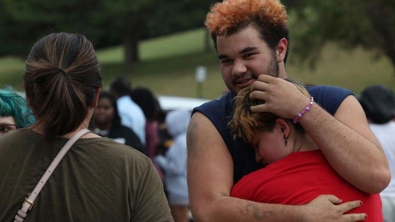 Artemis Else, right, hugs Angie Caswell as they wait outside...