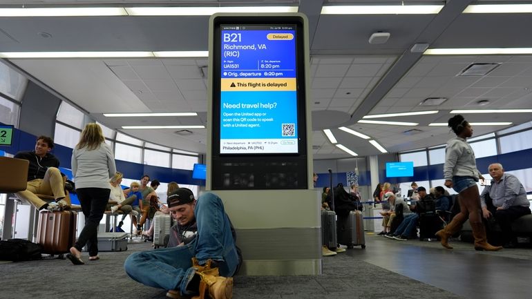 An information display near United gates shows a flight delay...