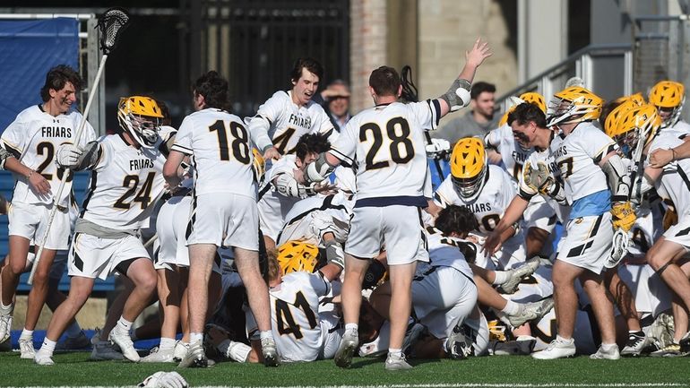 St. Anthony's teammates mob together in celebration after their 10-9...