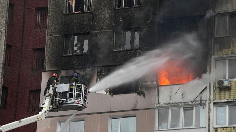 Firefighters work to extinguish a fire in an apartment building...