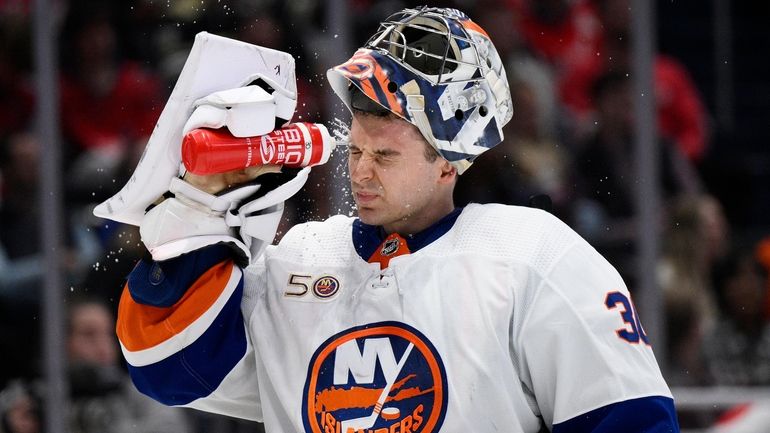 Islanders goaltender Ilya Sorokin sprays his face during a break...