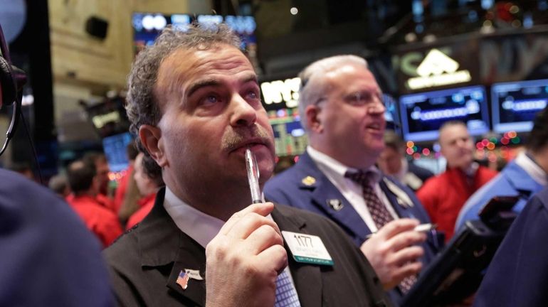 Trader Gerard Farco, left, works on the floor of the...