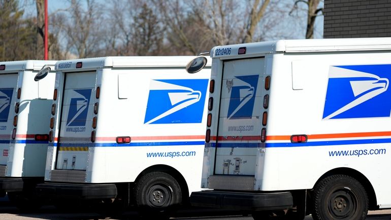 U.S. Postal Service trucks park outside a post office in...