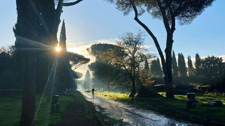 A man jogs on the ancient roman Appian Way in...