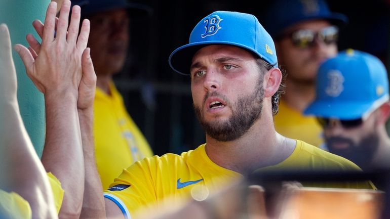 Boston Red Sox starting pitcher Kutter Crawford high-fives a teammate...