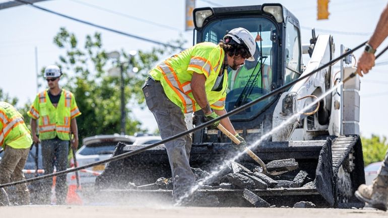 Members of Nassau's Department of Public Works repair a 20-foot-deep sinkhole on...