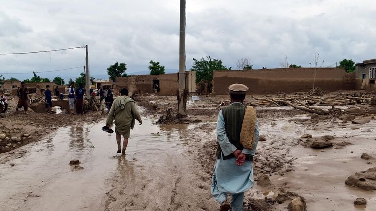 People are seen near to their damaged homes after heavy...