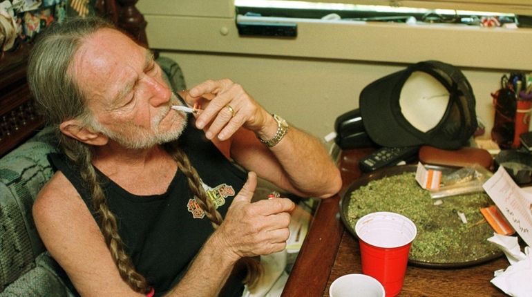 Willie Nelson takes a drag off a joint while relaxing...