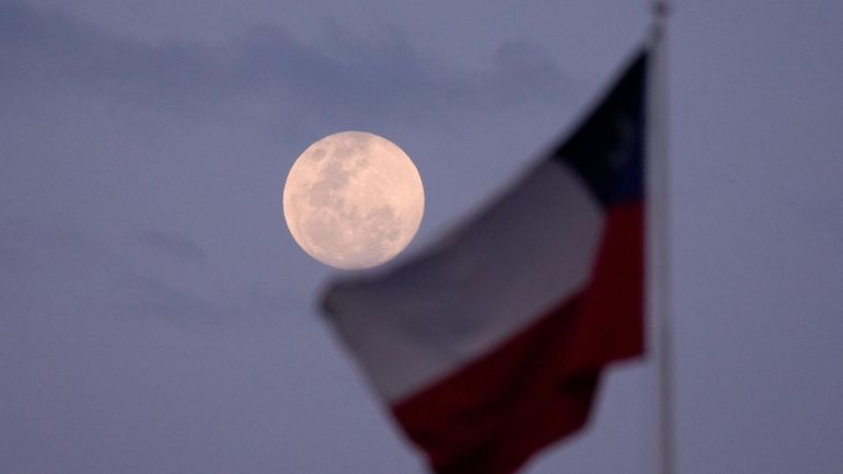 A Chilean national flag waves as the moon rises in...