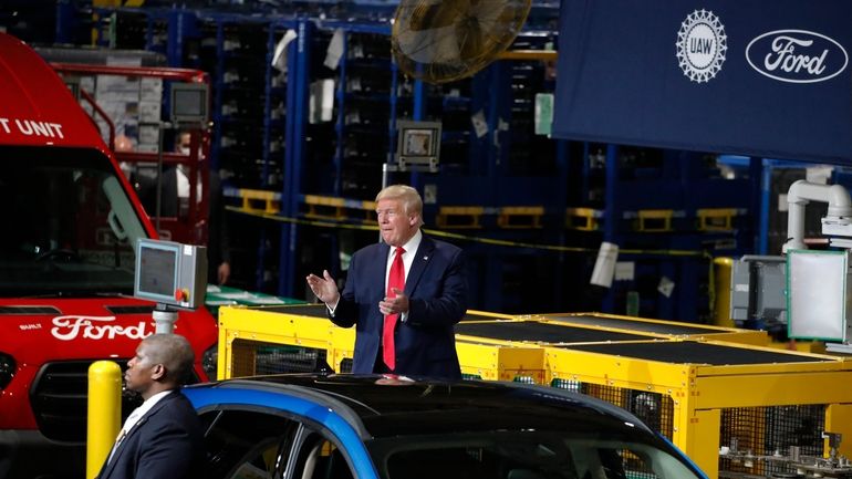 President Donald Trump claps as he walks to the podium...