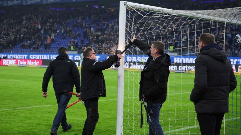 Stadium staff remove bicycle locks from goalposts with an angle...