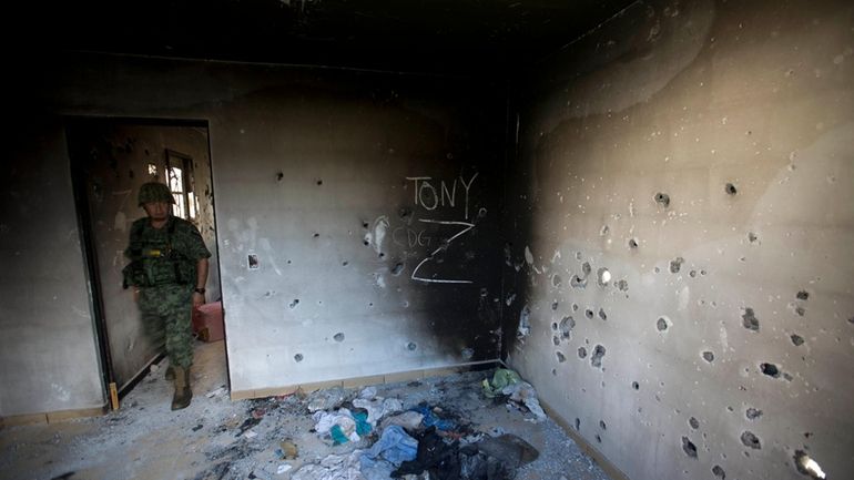 A soldier enters a bullet-riddled home covered by the initials...