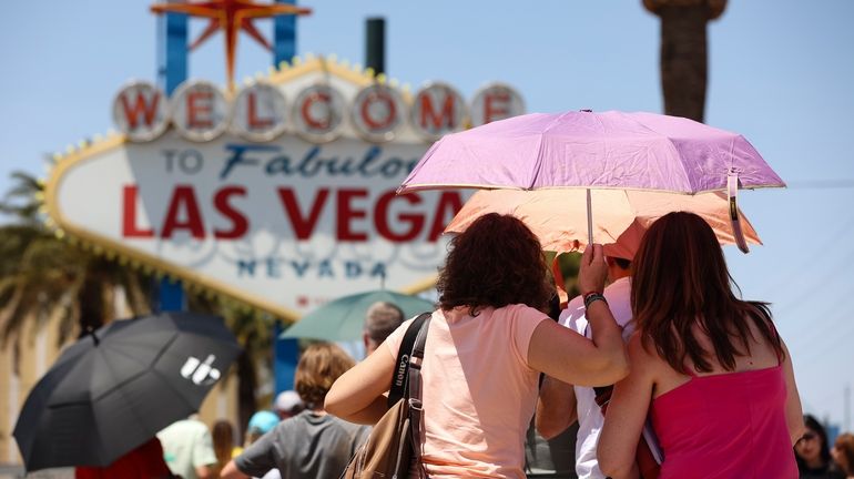 People use umbrellas to block the sun while waiting to...