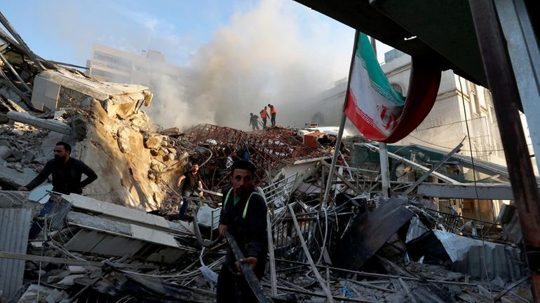 Emergency services work at a destroyed building hit by an...