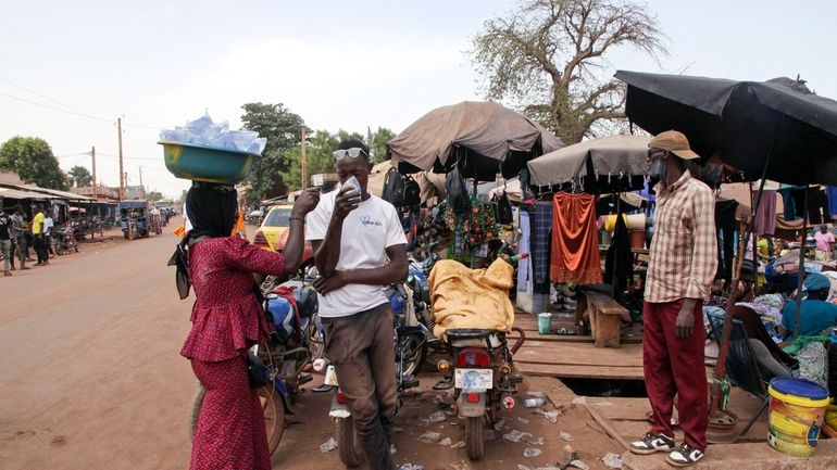 Amadou Coulibaly, a motorcycle taxi driver, drinks a sachet water...