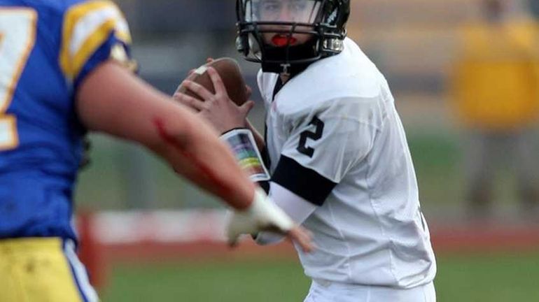 Syosset's QB #2 Daniel Ventricelli fires a pass while being...