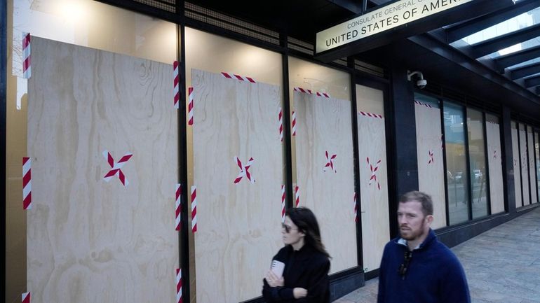 A couple walks past the boarded windows at the U.S....