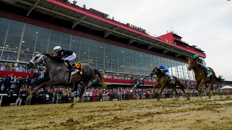 Jaime Torres, left, atop Seize The Grey, crosses the finish...