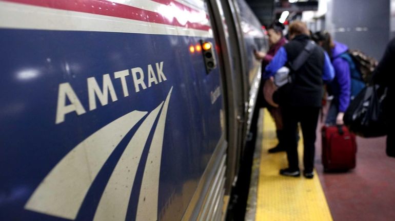 People board an Amtrak train at Penn Station in New...