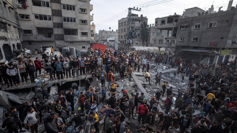 Palestinians search for bodies and survivors in the rubble of...