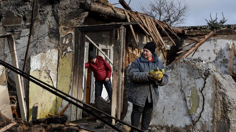 Inna, 71, holds food items found as she stands outside...