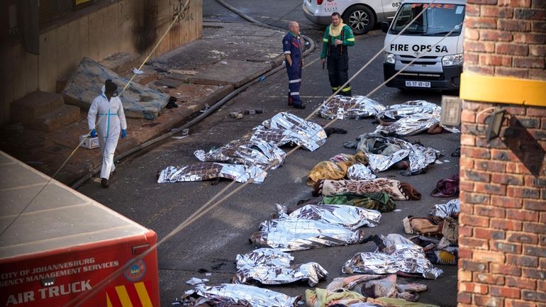 FILE — Medics stand by the covered bodies of victims...