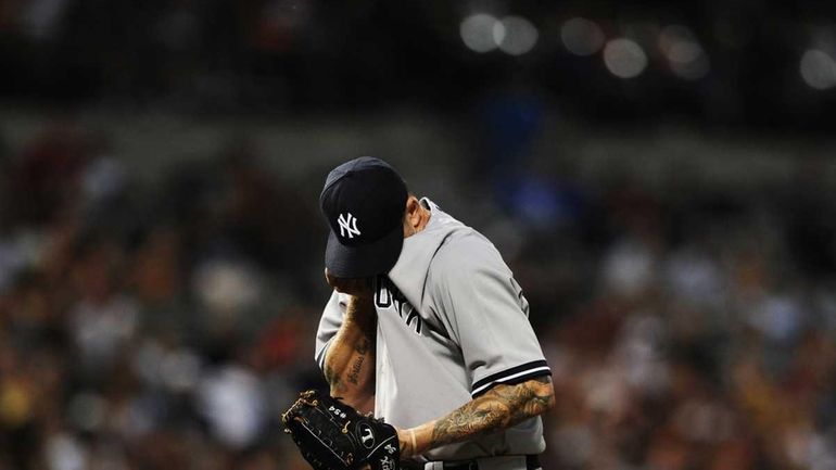 New York Yankees starting pitcher A.J. Burnett wipes sweat from...