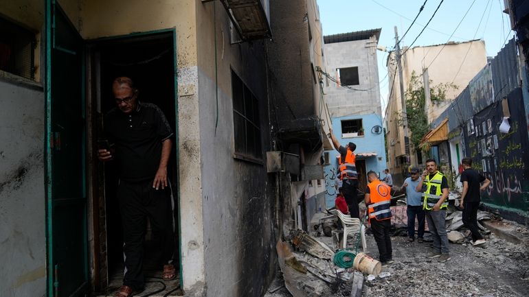 Palestinians municipality workers check a damaged house following an Israeli...