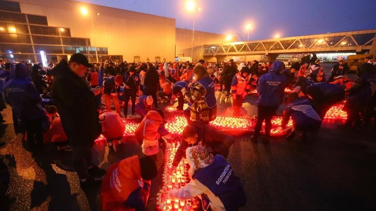 People light candles and lay flowers at a makeshift memorial...