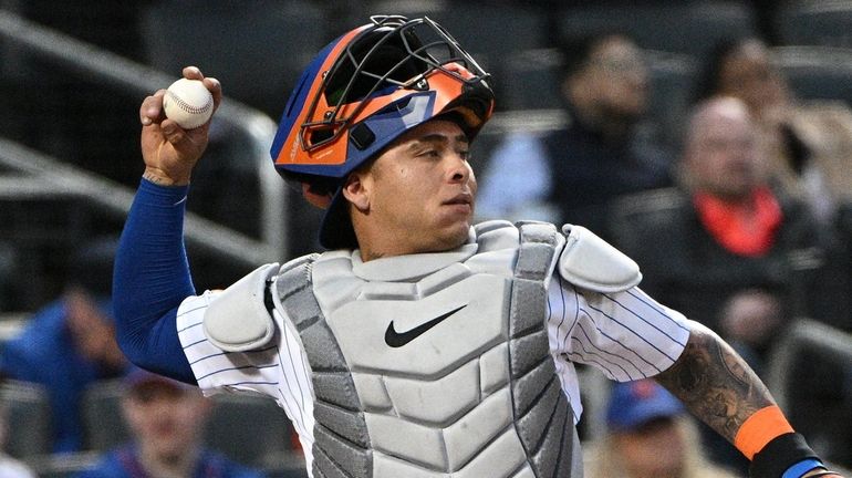 Mets catcher Francisco Alvarez throws to starting pitcher David Peterson...