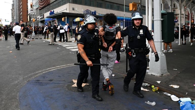 Police take a young person into custody during a riot...