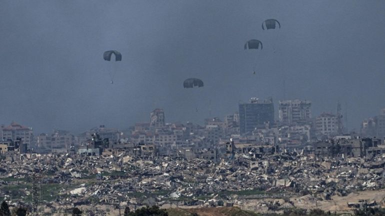 Parachutes drop supplies into the northern Gaza Strip, as seen...