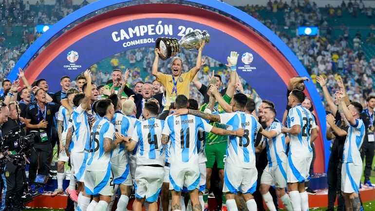 Argentina's staff member Mario De Stefano holds up the trophy...