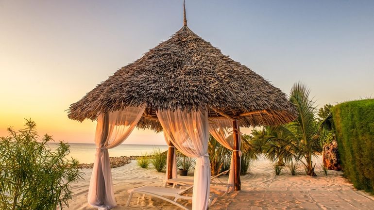 Beach lounge chairs at sunset, Zanzibar, Tanzania. 