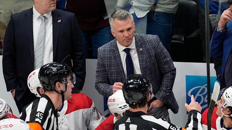 Montreal Canadiens coach Martin St. Louis, back, argues with referees...