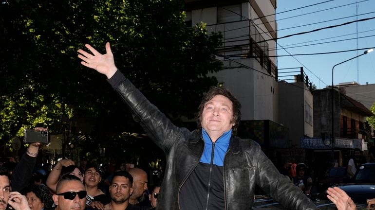 Presidential hopeful Javier Milei waves to supporters as he campaigns...