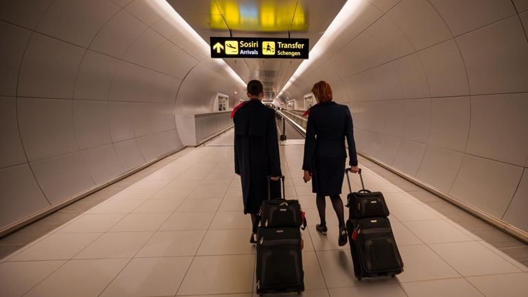 Flight attendants arriving at the Henri Coanda International Airport pass...