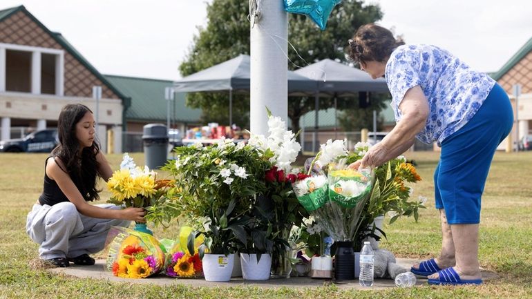 Freshman Ester Matias and a woman tend to flowers at a...