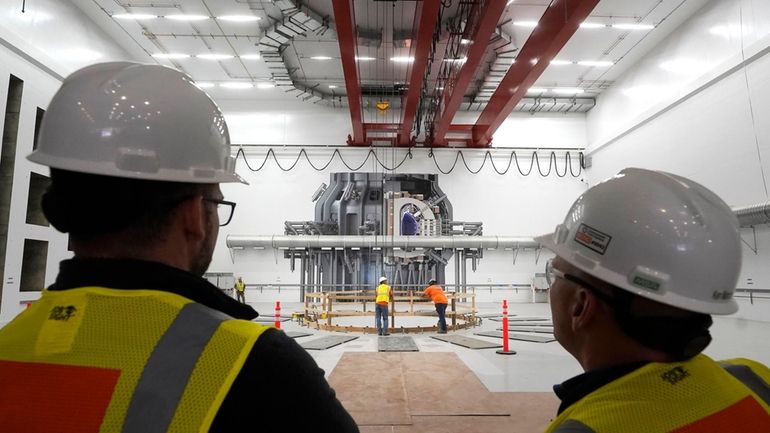 Workers, foreground, stand Wednesday, Oct. 11, 2023, in an area...