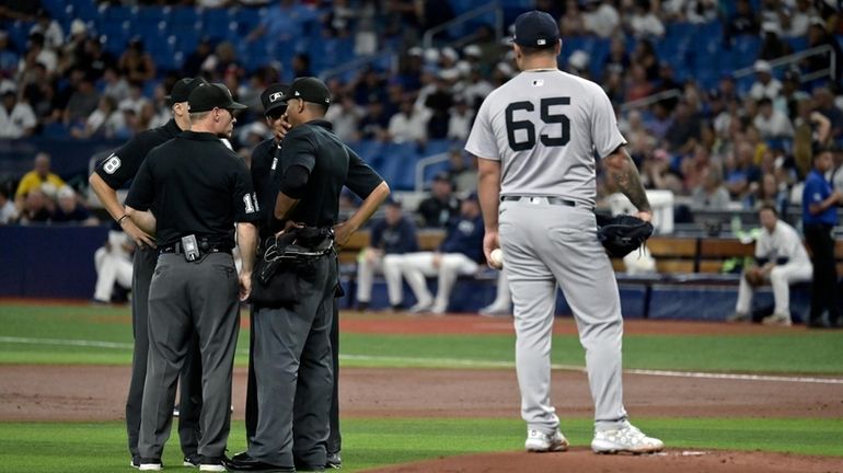 Yankees starter Nestor Cortes stands on the mound while umpires discuss...