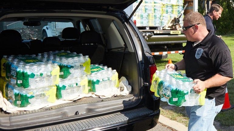 Scott Proser, from Suffolk County Fire Rescue, helps load water...