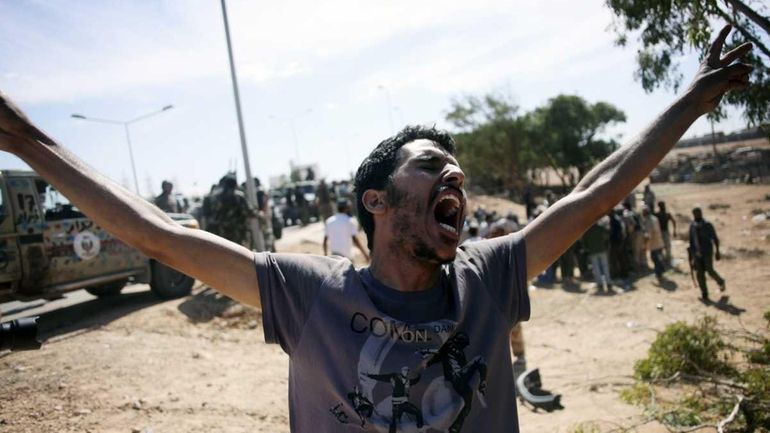 A revolutionary fighter celebrates in the captured town of Sirte,...