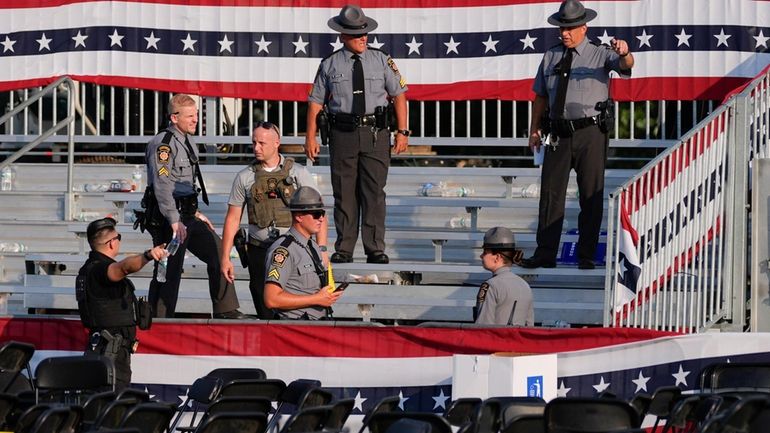 Law enforcement officers work at the campaign rally site for...