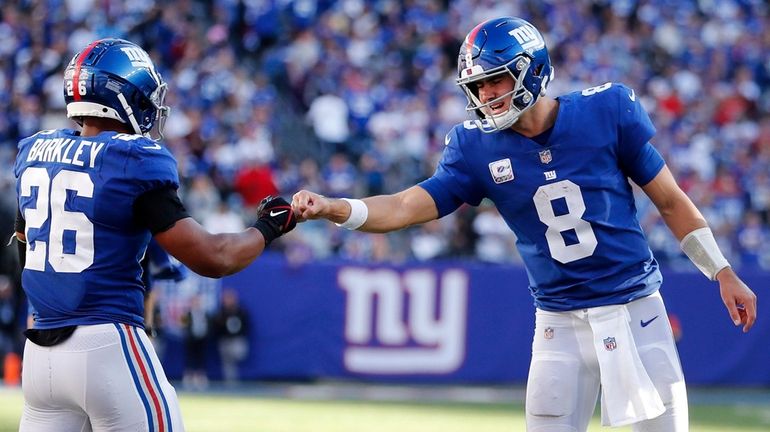 Daniel Jones #8 of the Giants fist bumps teammate Saquon Barkley...